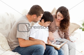 Happy family looking at a photo album together on the sofa 