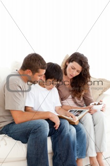 Adorable family looking at a photo album together on the sofa