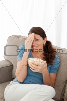 Pretty woman hiding her face while watching a horror movie