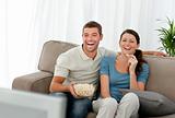 Lovely couple laughing while relaxing in front of the television