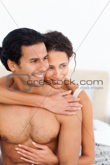 Passionate woman hugging her boyfriend sitting on their bed