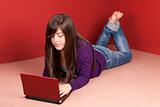 Young woman with laptop lying on floor at home