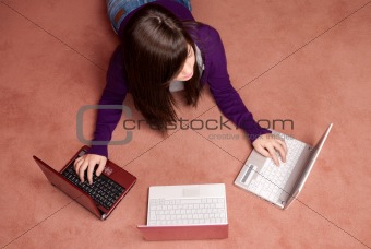 Young woman multitasking with three laptop lying on floor
