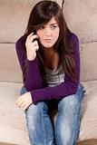 Young girl concerned talking by telephone bad news sitting on sofa