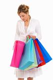 Young woman with shopping bags standing looking into bag isolated on white background