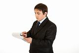 Serious young businessman making notes in document
