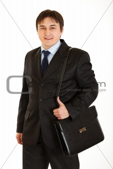 Smiling young businessman holding briefcase on shoulder
