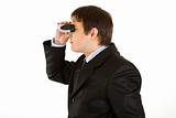 Interested young businessman looking through binoculars
