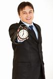 Smiling young businessman holding alarm clock in hand
