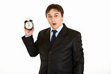 Shocked young businessman holding alarm clock. Lost time concept
