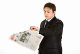 Young businessman looking at his watch while reading newspaper
