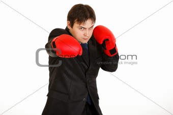 Punching furious young businessman with boxing gloves 
