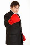 Confident young businessman with boxing gloves showing come on gesture
