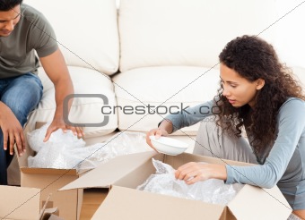 Happy woman packing glasses with her husband in the living-room