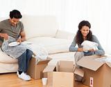Joyful couple packing glasses together in the living room