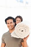 Hispanic couple carrying a carpet standing in the living room