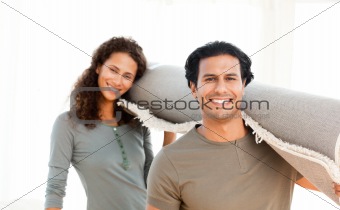 Cute couple carrying a carpet standing in the living room 