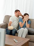 Lovely couple hiding their face from a horror movie 