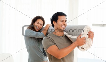Happy couple holding a carpet together in their new living-room 
