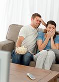 Terrified couple watching a horror movie