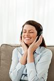 Cheerful businesswoman listening music on the sofa