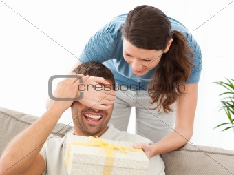 Happy woman giving a present to her husband in the living room