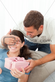 Happy woman receiving a gift from her boyfriend in the living room