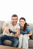 Happy couple playing video games together sitting on the sofa