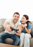 Cheerful woman encouraging her boyfriend playing video game