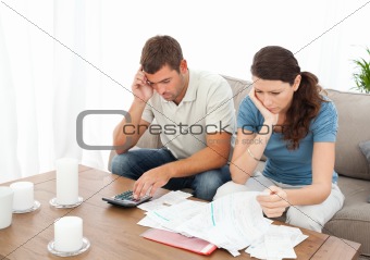 Desperate couple doing their accounts sitting on the sofa