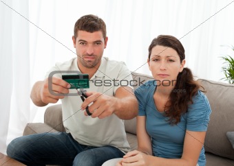 Worried couple cutting their credit card together sitting
