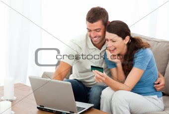 Happy couple looking at their accounts online sitting on the sofa