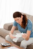 Worried woman looking at her bills sitting on her sofa