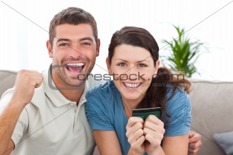 Portrait of a happy couple holding their credit card on the sofa