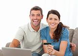 Cute couple with their laptop and credit card sitting 