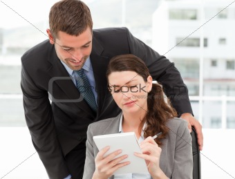 Happy businessman helping a businesswoman working at her desk