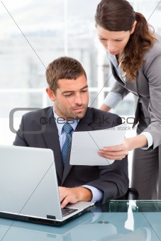 Two business people looking at a paper while working 