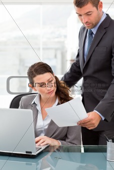Handsome manager showing a paper to a businesswoman while working
