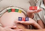 Close up of future parents holding cubes forming the words mom ,dad and baby