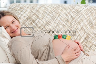 Smiling future mom with baby letters on the belly