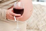 Close up of a pregnant woman with glass of red wine and cigarette