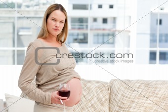 Young pregnant woman holding red wine and a cigarette