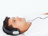 Peaceful man relaxing by listening music on his bed
