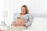Tranquil pregnant woman on her bed with baby letters on her belly