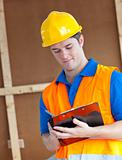 Handsome worker with hardhat taking notes on his clipboard