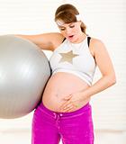 Surprised beautiful pregnant woman  holding  fitness ball and touching her belly
