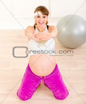 Smiling beautiful pregnant female doing fitness exercises  at home
