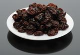 Raisin on a white plate on a black background