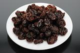 Raisin on a white plate on a black background