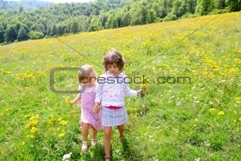 sister girls in meadow playing with spring flowers